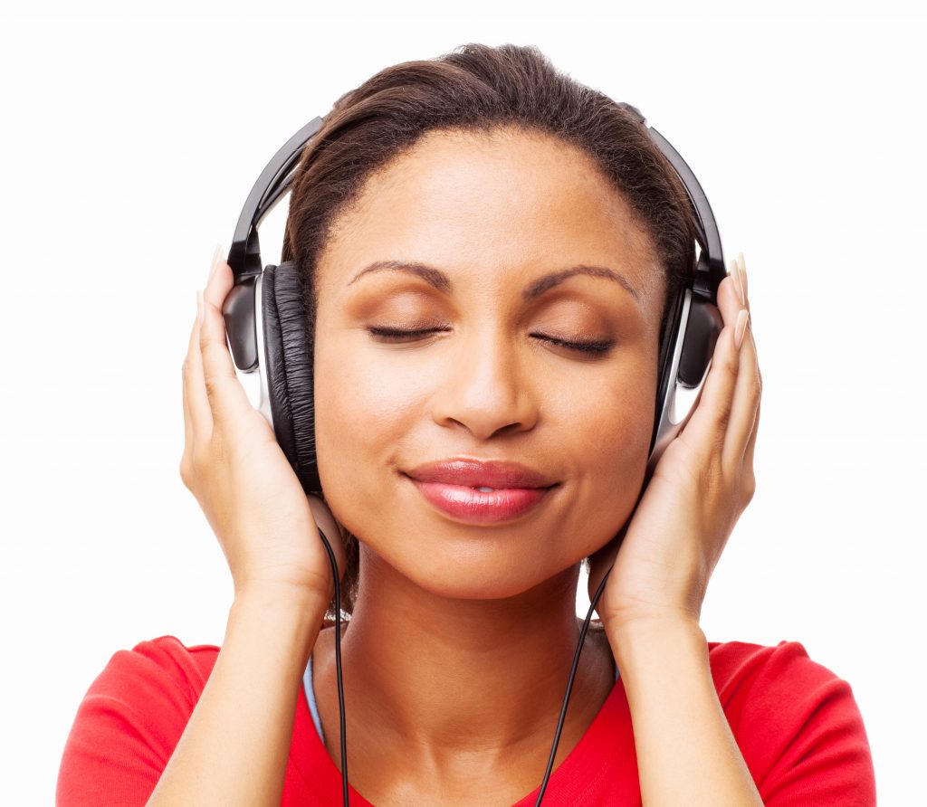 Close-up of a relaxed young African American woman listening music on MP3 player with eyes closed. Horizontal shot. Isolated on white.