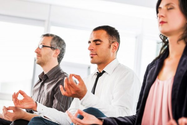 Successful businesspeople meditating in the office.