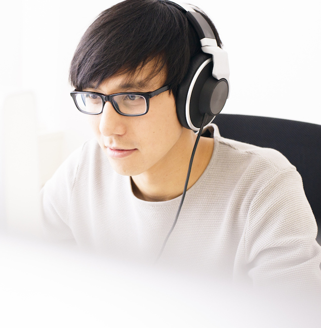 Young Professional Man Wearing Headphones Concentrating on Computer Screen