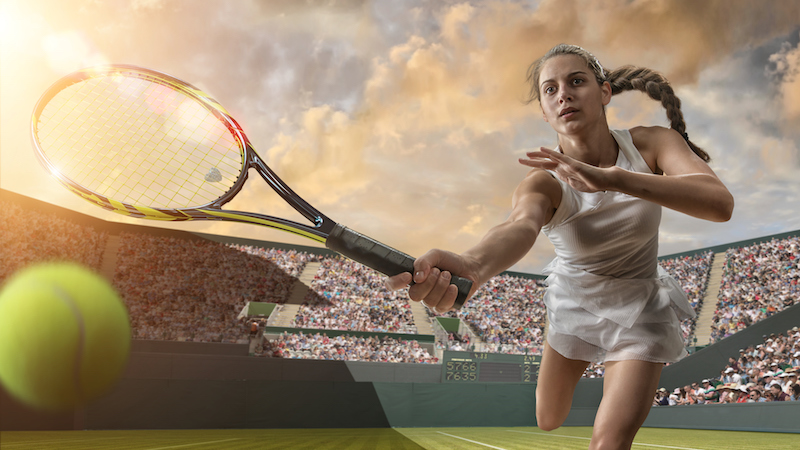 Female Tennis Player About To Strike Ball Mid action image of female tennis player having just hit a tennis ball during a tennis match. The action occurs in a generic outdoor tennis arena full of spectators under a bright cloudy summer sky at sunset. The tennis player is wearing generic white tennis dress and is playing with an unbranded racquet.