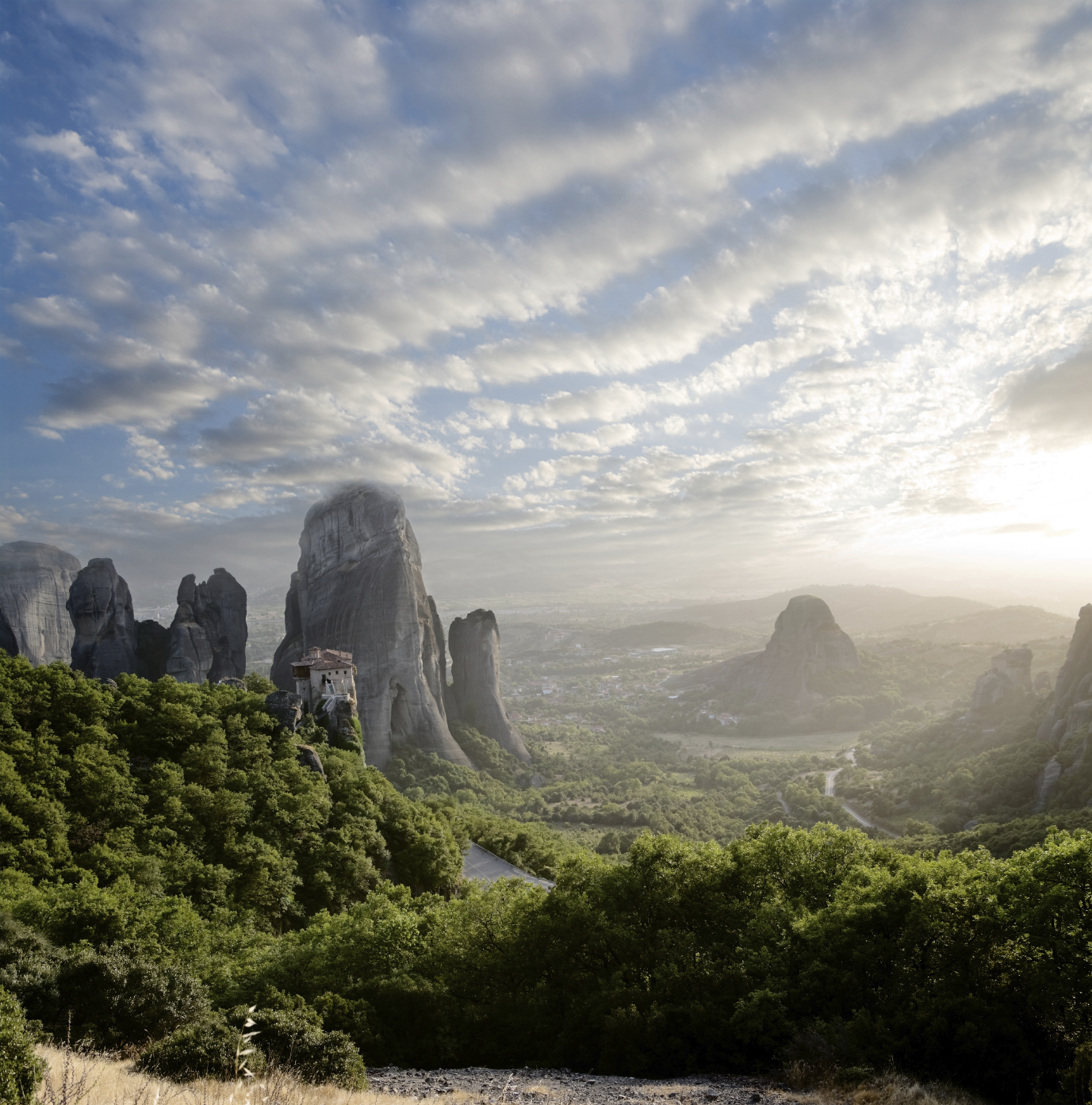 misty at sunset on rocks of Meteora, Greece misty at sunset of hot day on Moni Agias Varvaras Roussanou on top of rock Meteora, Greece