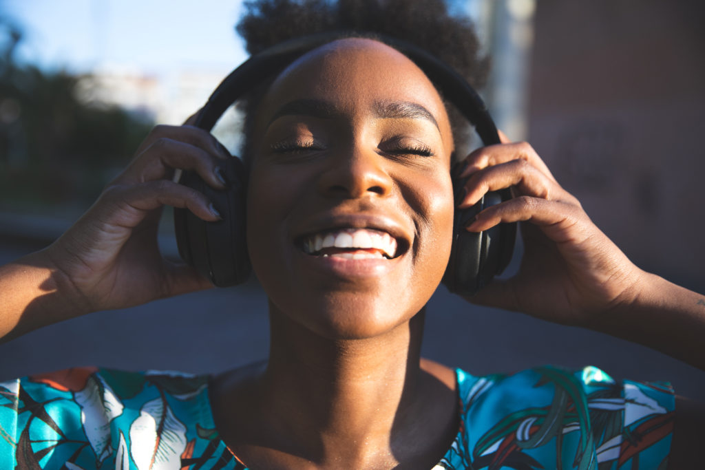 Happy woman dancing listening to music with big headphones outdoors