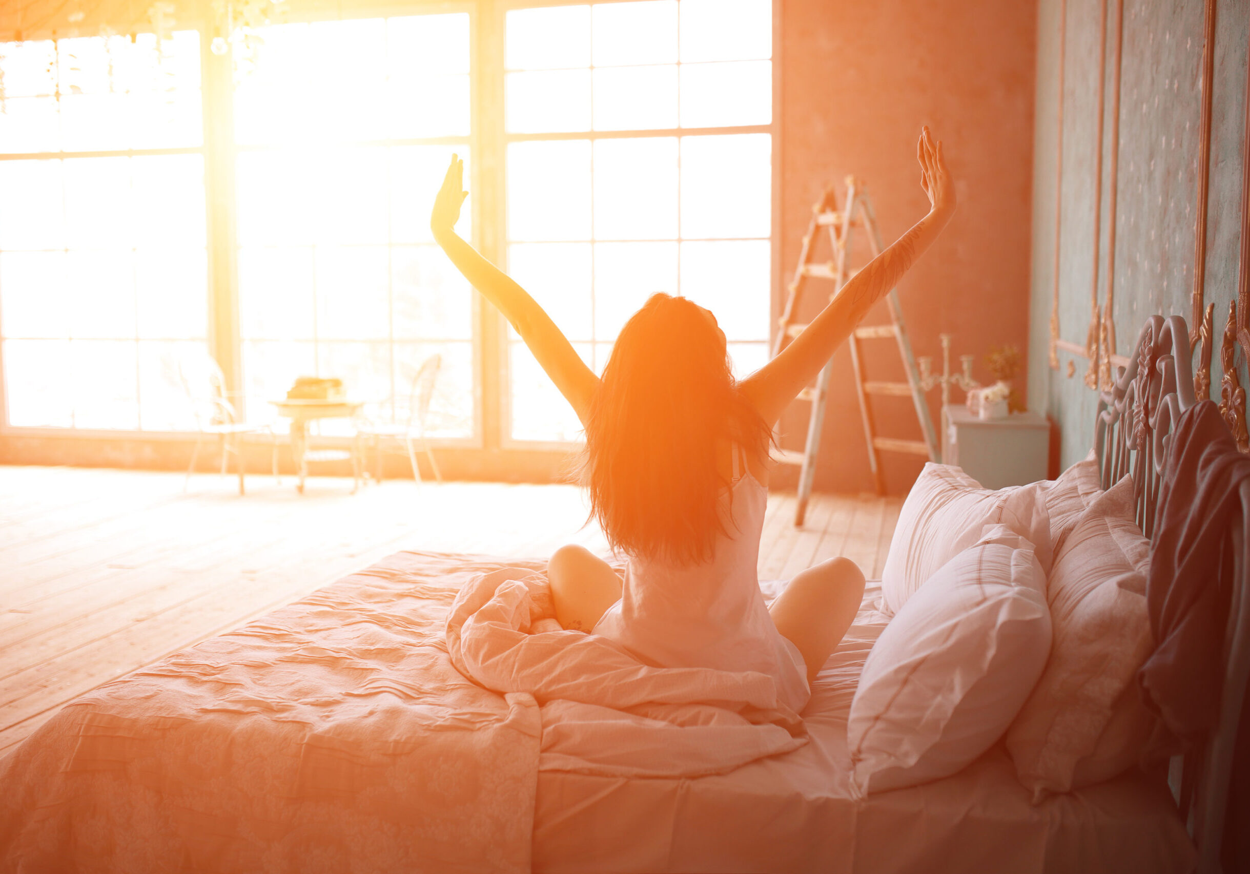 Woman stretching in bed after wake up, back view